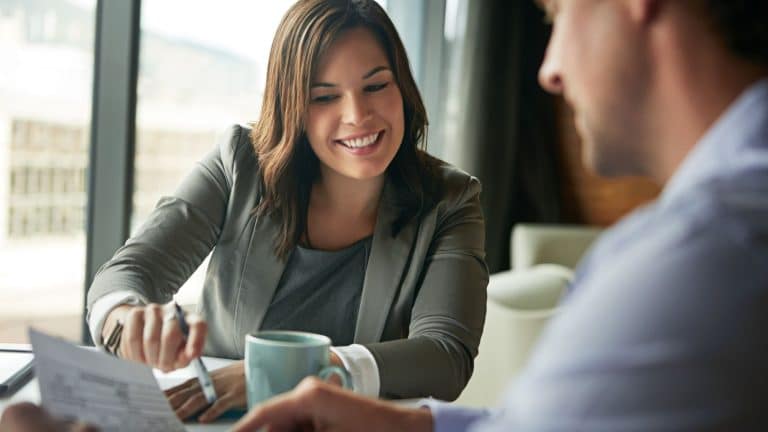 Two professionals discussing a financial report over a desk.