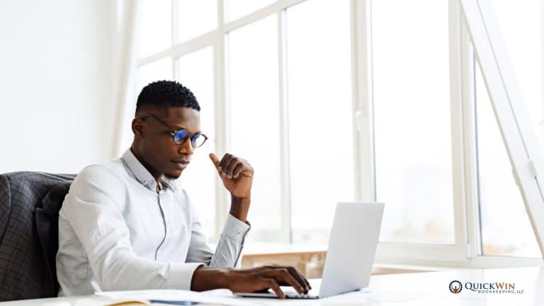 A business owner in his office on a laptop, reviewing his financials.